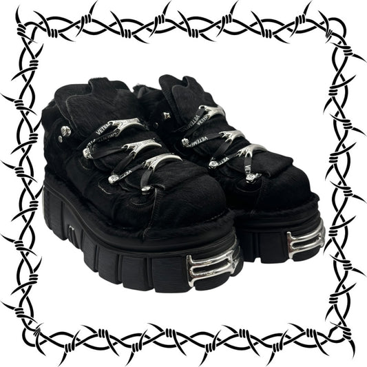 Black New Rock x Vetements platform boots with silver buckles on a barbed wire border
