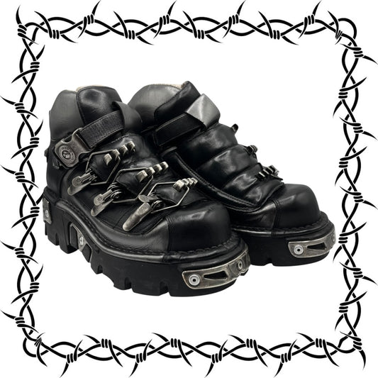 Black leather boots with metal accents on a white background with barbed wire border