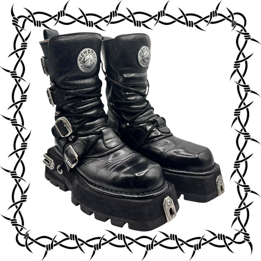 Pair of New Rock black leather boots with buckles and platform soles on a barbed wire border.
