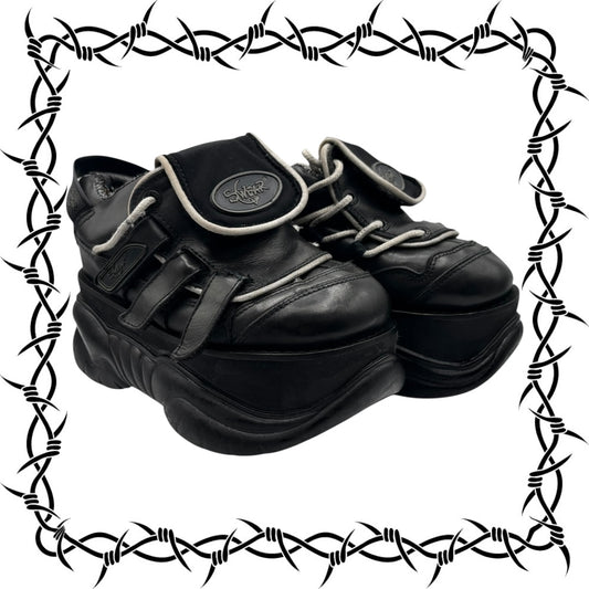 Pair of Swear London black leather shoes with a brand logo on a barbed wire border.