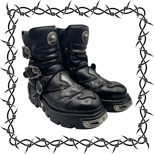 Pair of black leather boots with decorative elements on a barbed wire border.