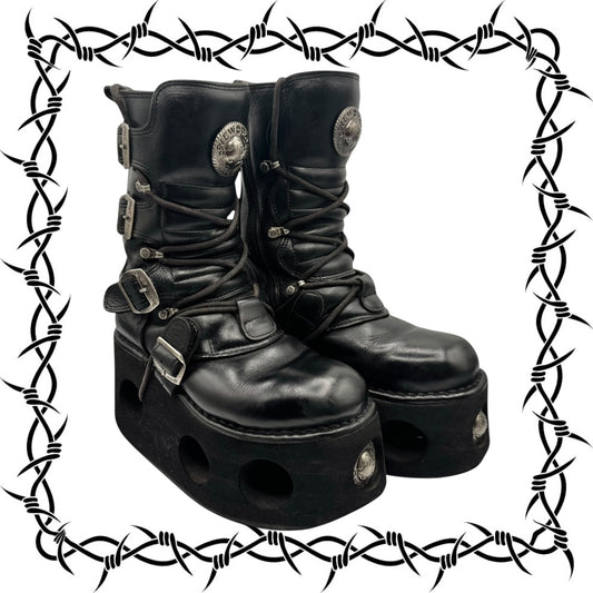 Pair of black leather boots with buckles and platform soles on a white background.