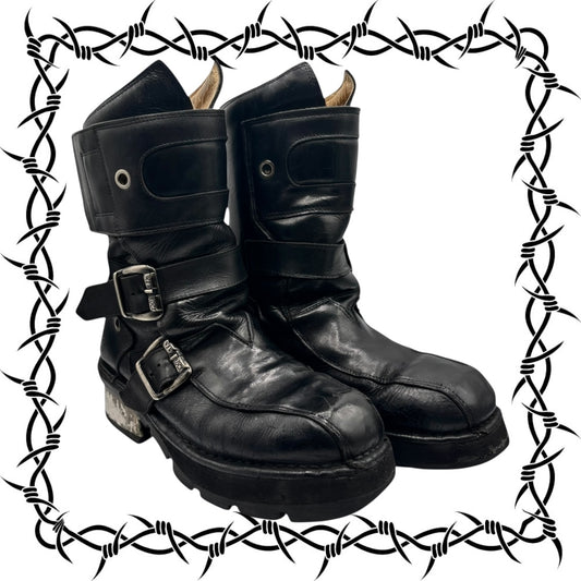 Pair of black leather boots with buckles on a white background with barbed wire border.