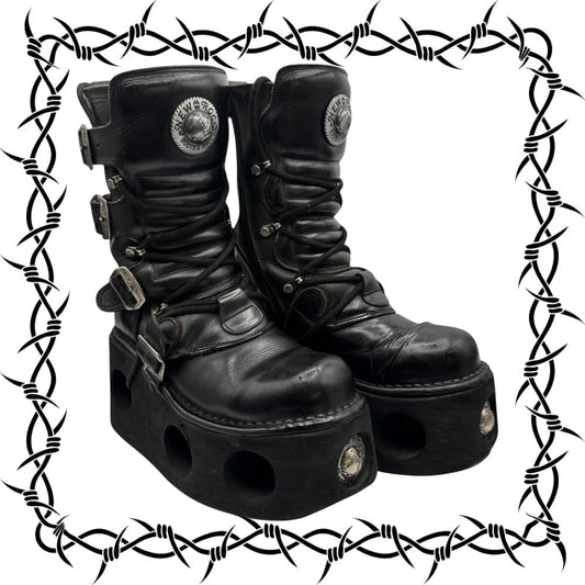Pair of black leather platform boots with decorative elements on a white background with barbed wire border.