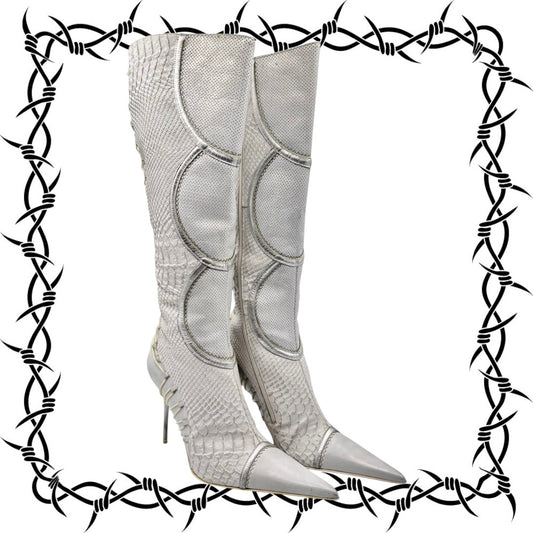 White El Dantes high-heeled boots with metallic accents on a white background with barbed wire border.